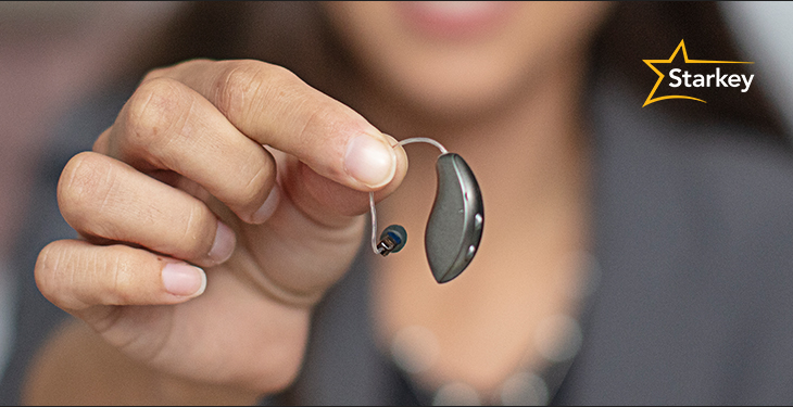 Close-up image of woman's hand holding standard hearing aid